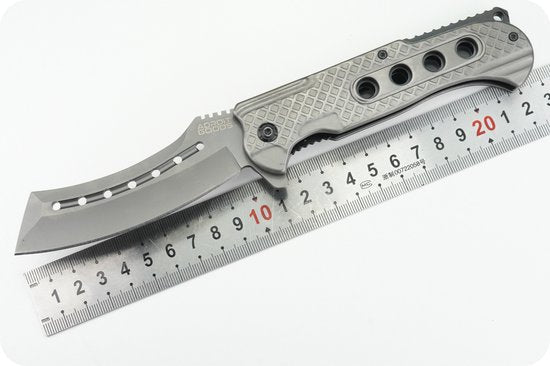 vouwmes met metalen handvat en geperforeerd lemmet naast een metalen liniaal