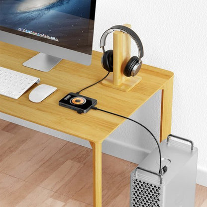 Modern bureau met computer, hoofdtelefoon op houten standaard en externe geluidskaart