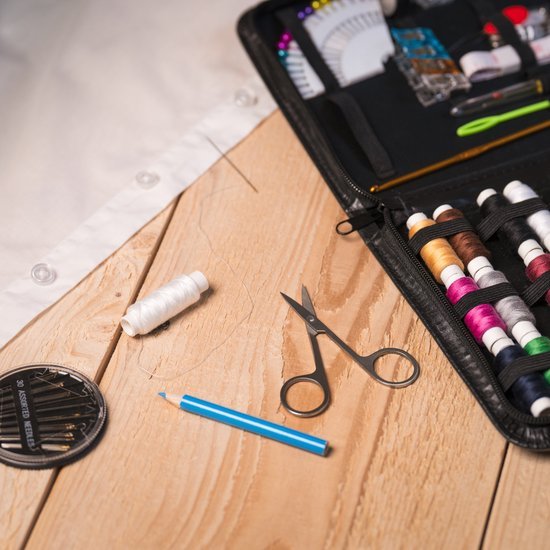 Naaigerei met schaar, gekleurde garens en een blauwe markeerstift op houten tafelblad