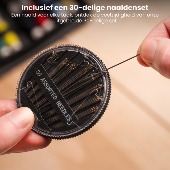Hand houdt een ronde doos met een 30-delige naaldenset en een losse naald vast
