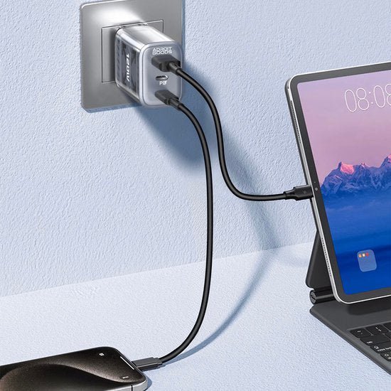 Zwarte oplaadkabel met dubbele aansluiting aangesloten op stopcontact en laptop op bureau