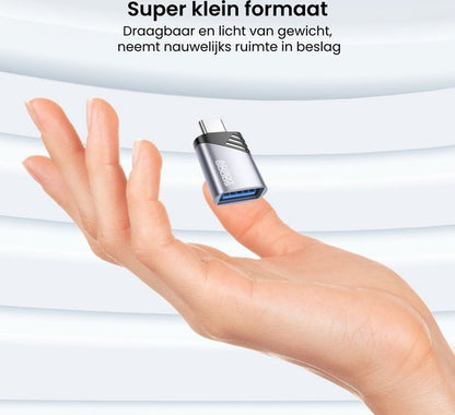 Hand houdt een klein zilverkleurig USB-adapter met blauwe aansluiting vast