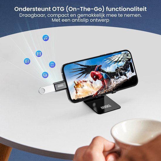 Smartphone op standaard met aangesloten USB-stick en hand met koffiekopje erbij