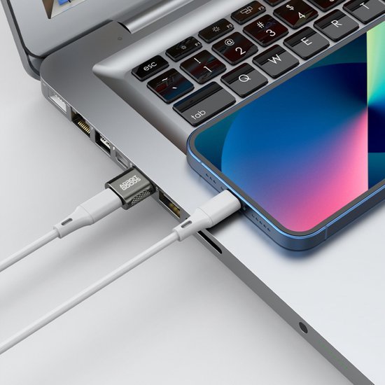 Laptop met twee aangesloten witte oplaadkabels, een verbonden met een smartphone en een met een usb-stick