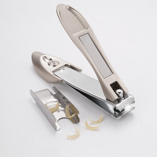 nikkelkleurige nagelknipper met ingebouwde vijl en verwijderde nagelresidu's erop