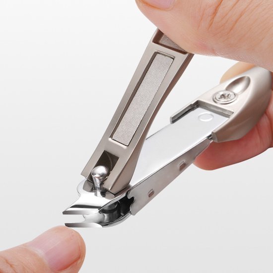 Hand die een metalen nagelknipper gebruikt om een vingernagel te knippen dichtbij een witte achtergrond