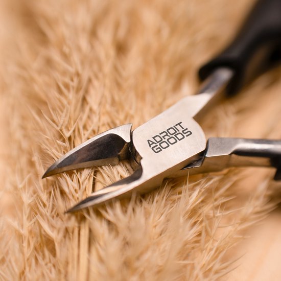 Detailfoto van metalen tang met scherpe punt en AdroitGoods logo op zachte achtergrond