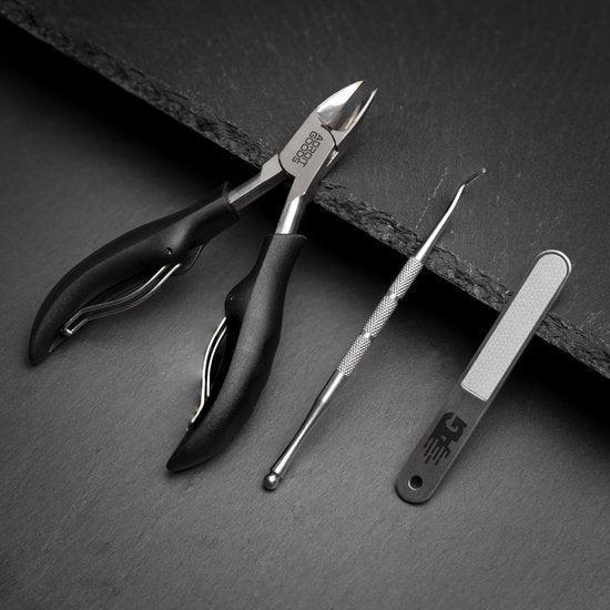 Zwarte professionele nagelknipper, roestvrijstalen nagelreiniger en vijl op donkere ondergrond