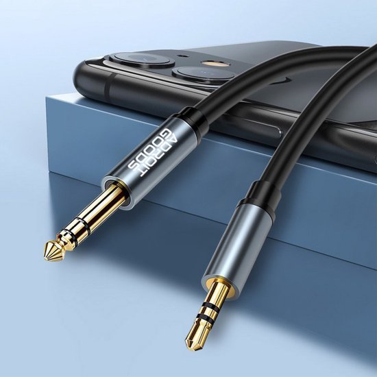 zwarte audiokabel met 3,5 mm en 6,35 mm gouden connectoren naast een smartphone