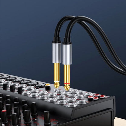 Twee zwarte kabels met zilveren connectors steken in een professionele audio mixer panel
