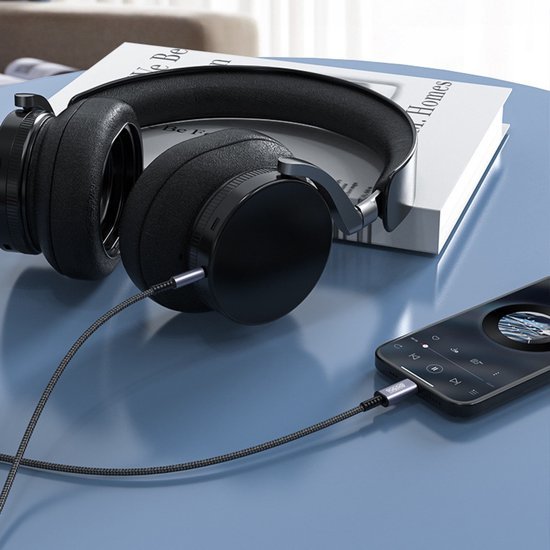 Zwarte over-ear koptelefoon met stoffen kabel aangesloten op een muziekspeler op tafel