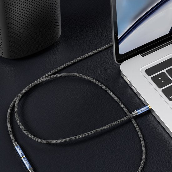 grijze gevlochten audiokabel verbonden met een laptop en een zwarte speaker op een zwarte ondergrond