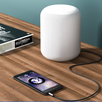 Wit cilindervormig draadloos speakerapparaat op houten tafel met verbonden smartphone.