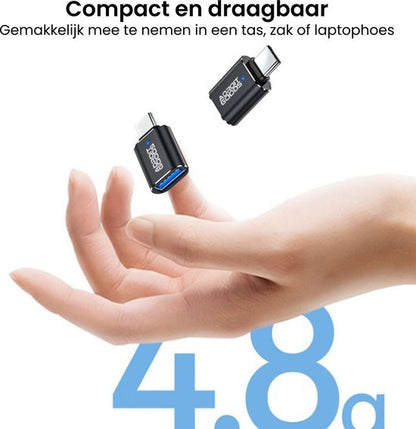 Hand houdt twee compacte, draagbare zwarte adapters met blauwe USB-ingang vast.
