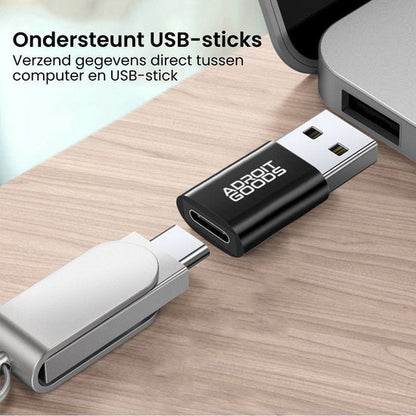 Close-up van zwarte USB-adapter en USB-stick op een houten oppervlak naast laptoppoort