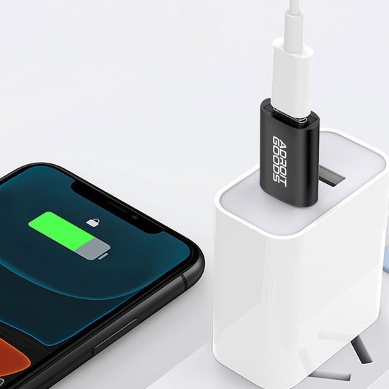 Zwarte USB-adapter met wit oplaadkabel aangesloten op wit stopcontact naast smartphone met opgeladen batterij