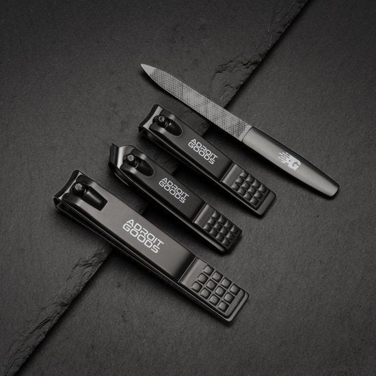 Drie zwarte nagelknippers met Adroit Goods logo en een metalen vijl op een donker oppervlak