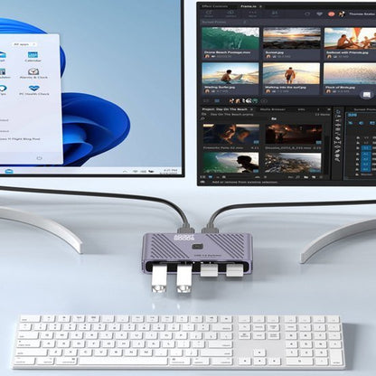 Twee monitoren aangesloten op een USB-hub met meerdere poorten naast een wit toetsenbord op een bureau.