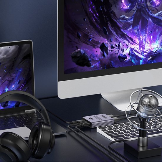 Computerscherm en laptop met kleurrijk ruimtebeeld, koptelefoon en microfoon op bureau