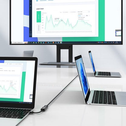 Twee open laptops en een groot computerscherm op een witte tafel met grafieken op het scherm