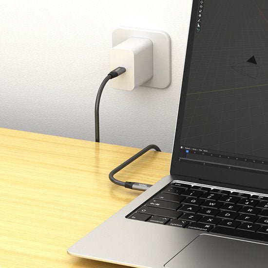 Zwarte oplader aangesloten op laptop met USB-C kabel en wit stopcontact aan muur