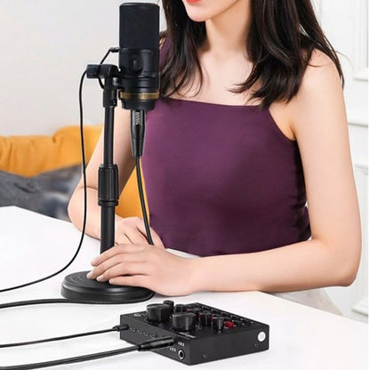 Vrouw in paarse top gebruikt microfoon en audio-interface op witte tafel binnenhuis