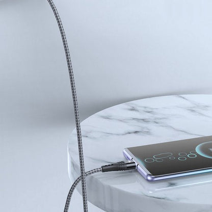 Flexibele oplaadkabel aangesloten op smartphone die op een marmeren tafel ligt