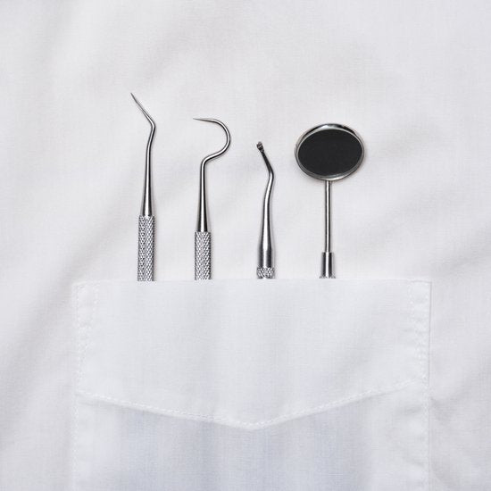 Tandheelkundige gereedschappen netjes in het zakje van een witte jas geplaatst