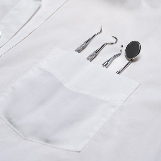 Witte jas met vier professionele tandartsgereedschappen in borstzak van dichtbij bekeken.