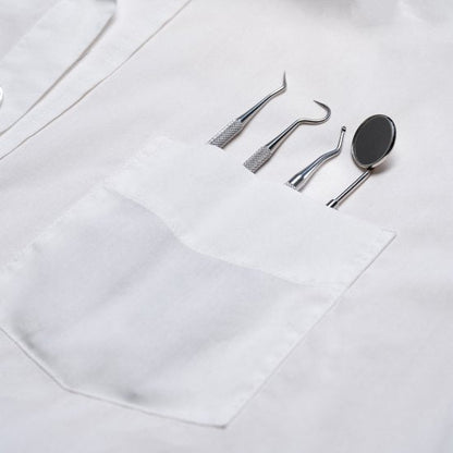 Witte jas met vier professionele tandartsgereedschappen in borstzak van dichtbij bekeken.