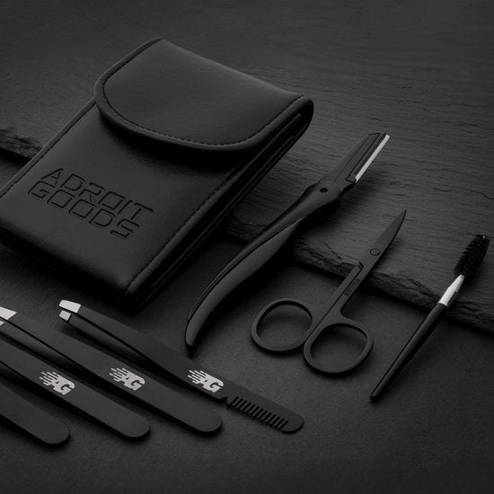 Zwart verzorgingsset met etui, scheermesje, schaar, pincet en kam op donkere ondergrond