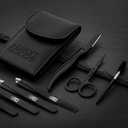 Zwart verzorgingsset met etui, scheermesje, schaar, pincet en kam op donkere ondergrond