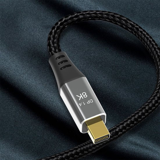 Zwarte gevlochten kabel met zilveren connector en gouden contactpunten op donkere achtergrond