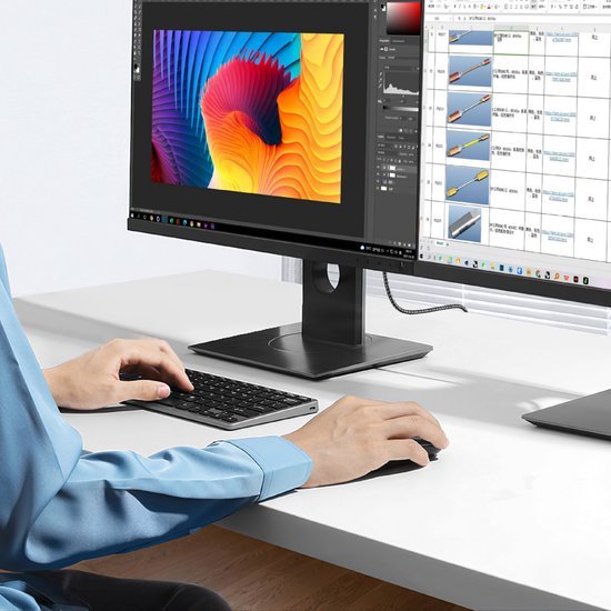 Persoon die met muis en toetsenbord werkt op bureau met dual-monitor setup
