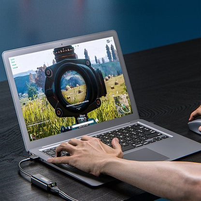 Hand bedient laptop met gameplay zichtbaar op scherm en een verbonden randapparaat