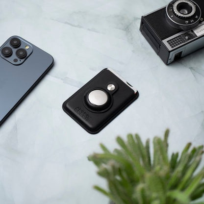 Zwart leren telefoonhouder met magneetring tussen moderne smartphone en vintage camera op marmeren oppervlak