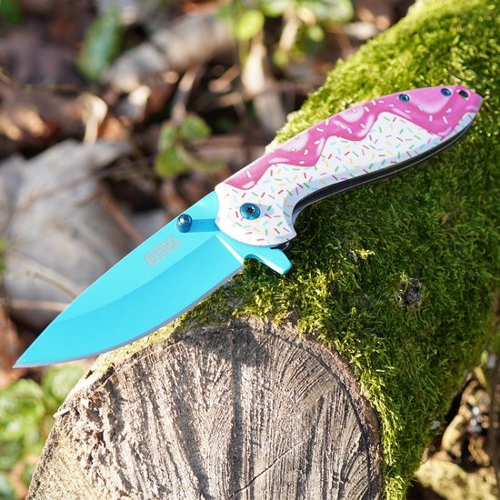 Open vouwmes met felblauw lemmet en kleurrijk handvat op mosbedekte boomstronk