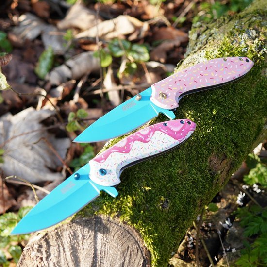 Twee kleurrijke opvouwbare messen met blauw lemmet en roze handvat met glazuur en sprinkels, op mos.