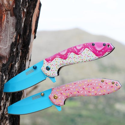 Twee kleurrijke zakmessen met blauw lemmet en handvatten in roze met spikkels, tegen boom en natuur achtergrond
