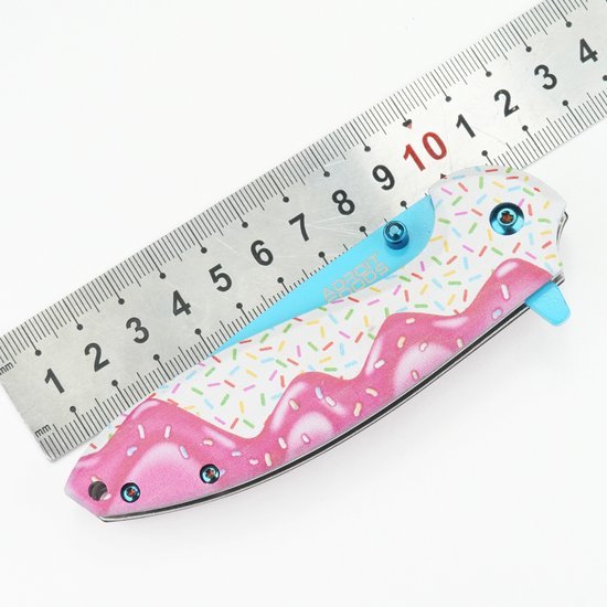 Opgevouwen mes met kleurrijk ijsjesspraypatroon naast metalen liniaal in centimeters.