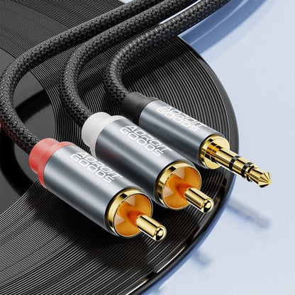 Draadloze AdroitGoods audiokabel met gouden RCA en 3,5 mm connectoren naast een zwarte plaat