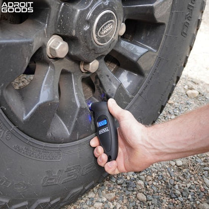 Hand die digitale bandenspanningsmeter gebruikt op auto-velg met Land Rover wiel logo