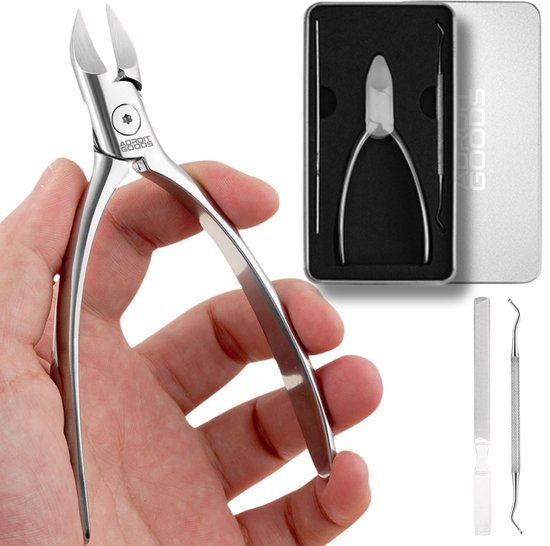 Hand die een roestvrijstalen nagelknipper vasthoudt naast een manicure gereedschapsset in een doosje