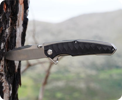 Zakmes met zwart handvat in de bast van een boom, natuur op de achtergrond