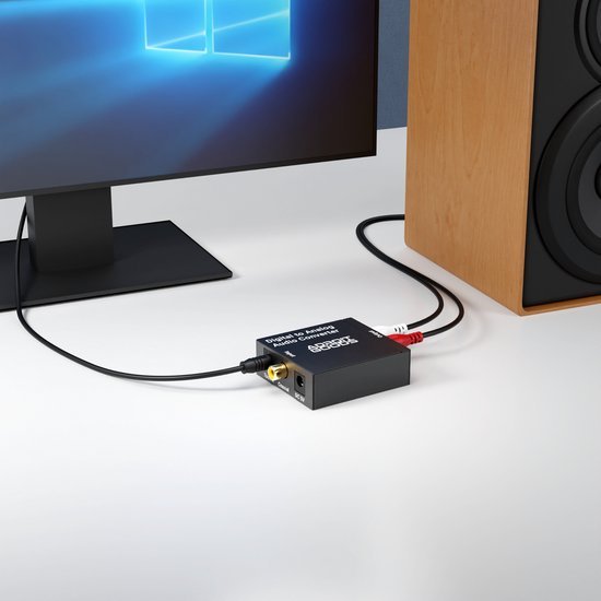 Zwart audioconverter apparaat verbonden met computer en houten luidspreker op witte ondergrond