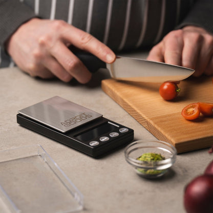 Persoon snijdt cherrytomaatjes op houten plank met digitale keukenweegschaal ernaast