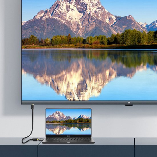 Laptop verbonden met grote scherm waarop berglandschap en reflectie in water te zien is