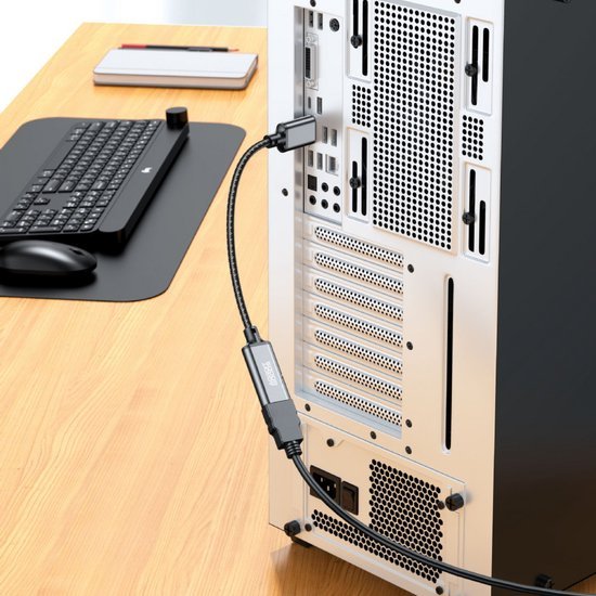 achterkant computer met aangesloten kabel op houten bureau naast toetsenbord en muis