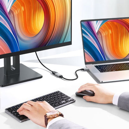 Handen bedienen toetsenbord en muis verbonden met laptop en extern scherm met kleurrijk beeld