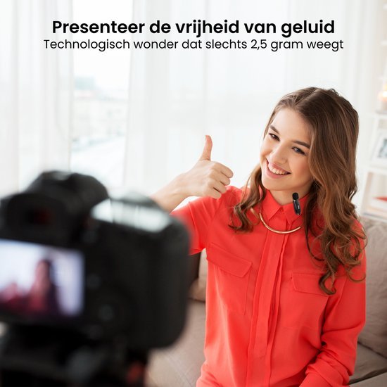 Vrolijke vrouw met draadloze microfoon geeft duim omhoog tijdens opname in lichte kamer